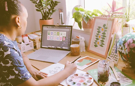 Freelance digital designer Emma Make in her studio designing on a laptop
